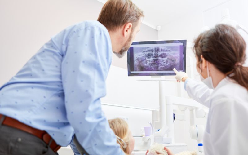 A dental professional is using advanced technology to capture X-ray images of a patient's teeth and jaw.