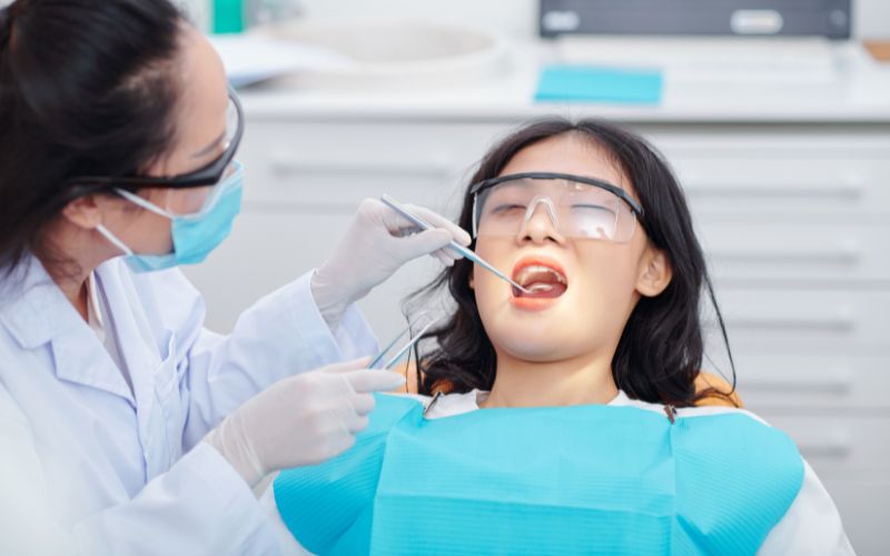 The patient is seated in the dental chair while the dentist performs a thorough examination of their teeth and gums.