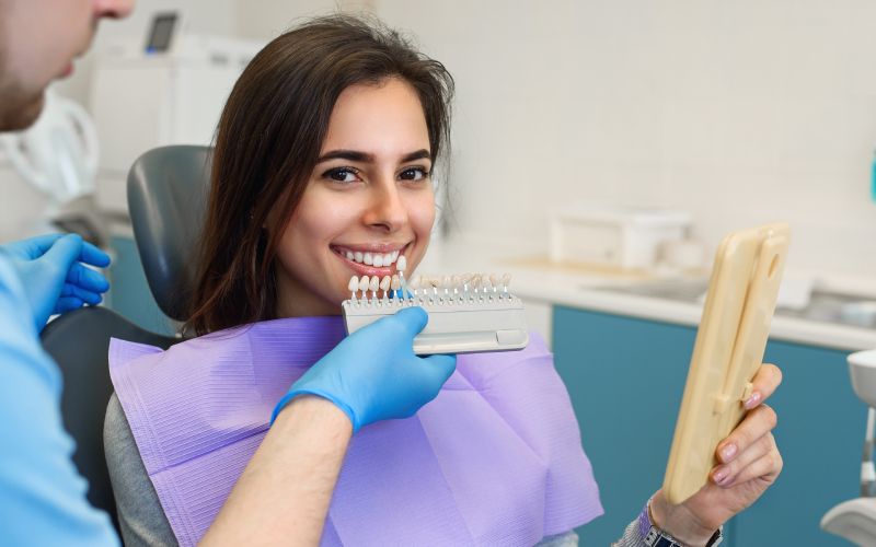 dentist matching patients teeth color with palette in office