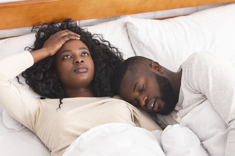 frustrated-young-woman annoyed by husband snoring loudly in bed