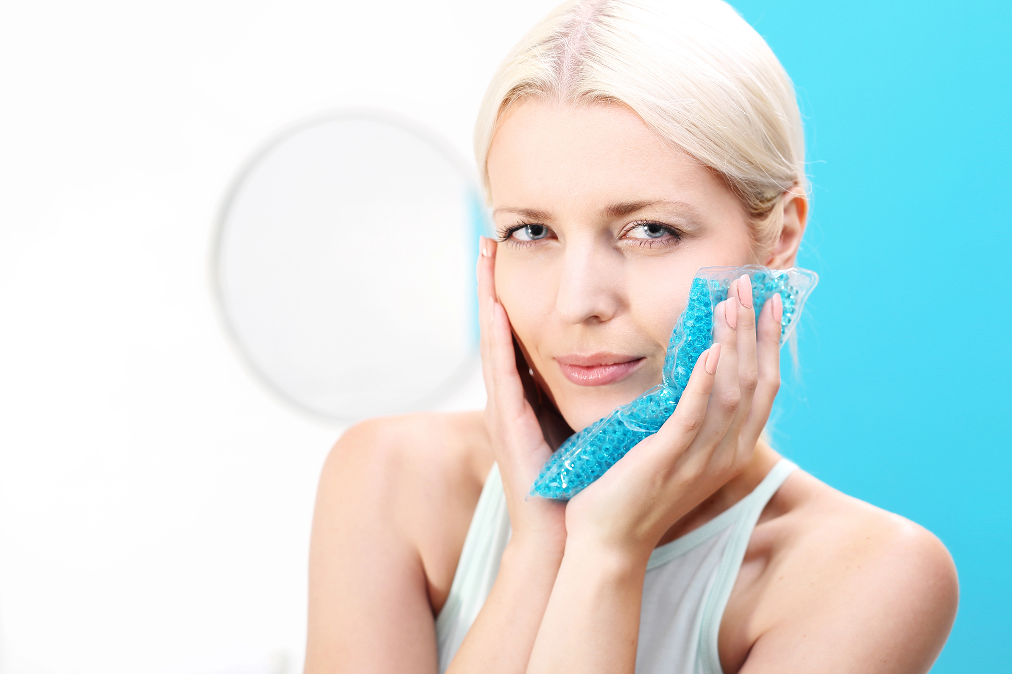 Person applying cold compress to sore tooth for toothache