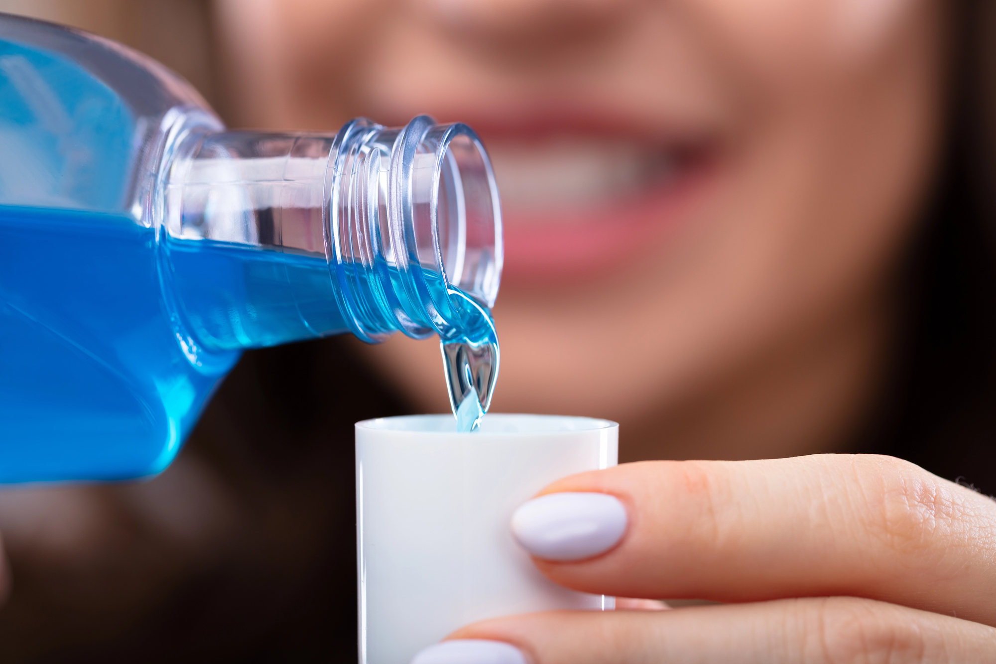 Woman's hand pouring mouthwash into bottle cap